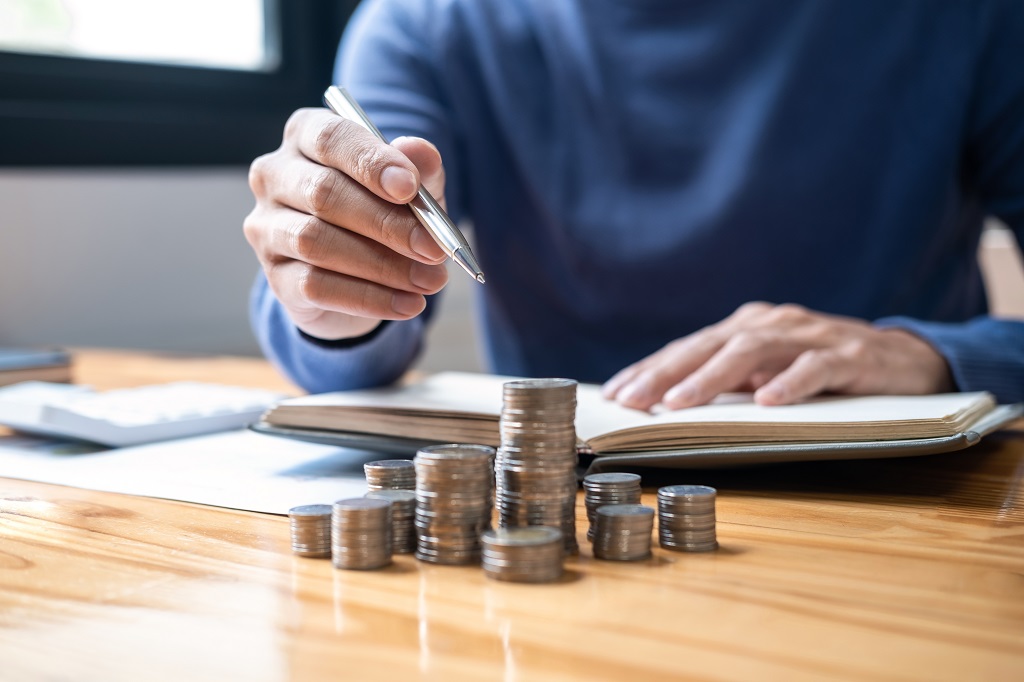 Person reviewing financial documents with stacked coins representing proof of funds for international travel