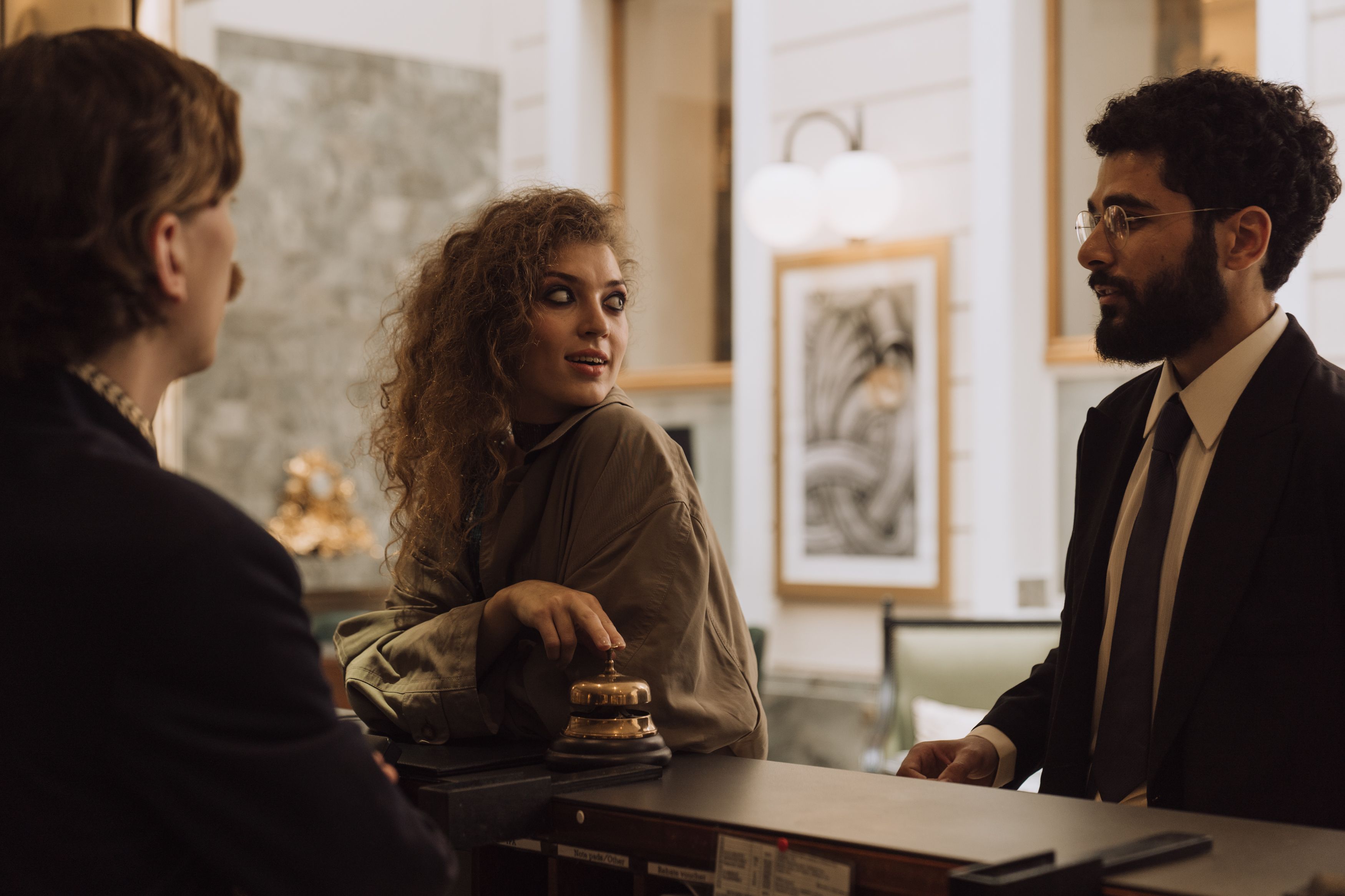 Hotel guests speaking with reception staff in a polished luxury hospitality setting.
